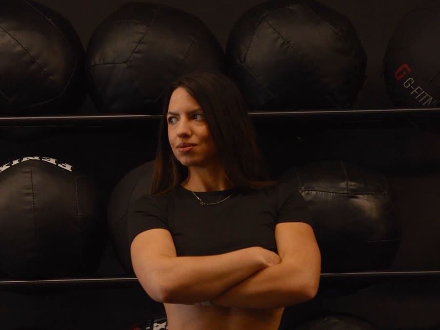 Maia Soldano con ropa negra y los brazos cruzados, apoyada en una pared de balones medicinales, con expresión seria.